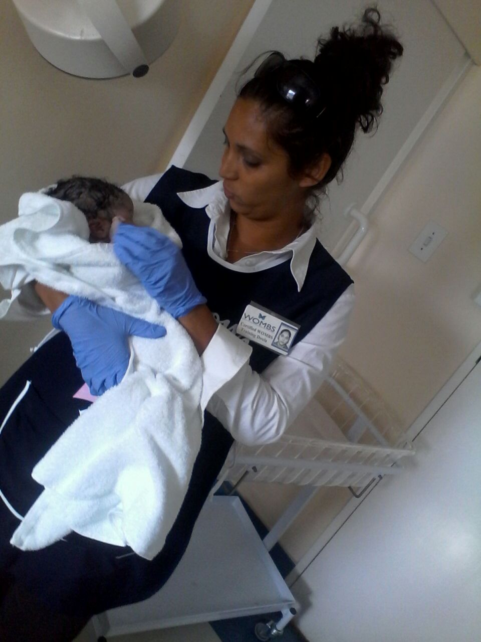 A certified WOMBS doula holding a towel-wrapped newborn